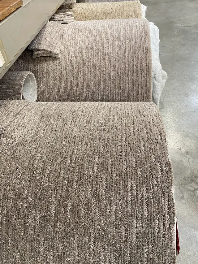 Close-up of two rolls of taupe textured carpet