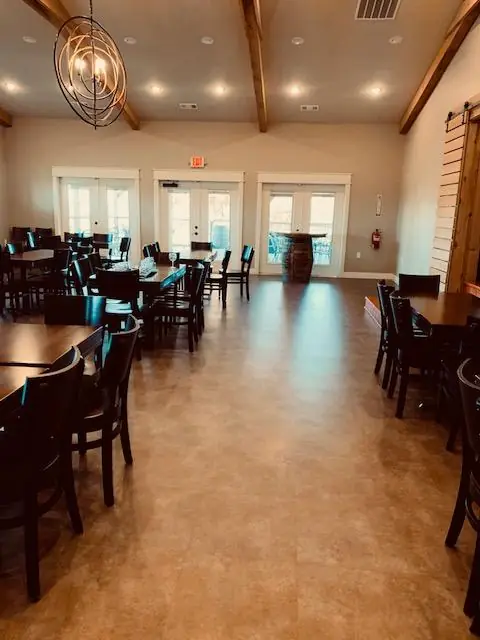 Large beamed hall with dining tables set over a warm tile floor