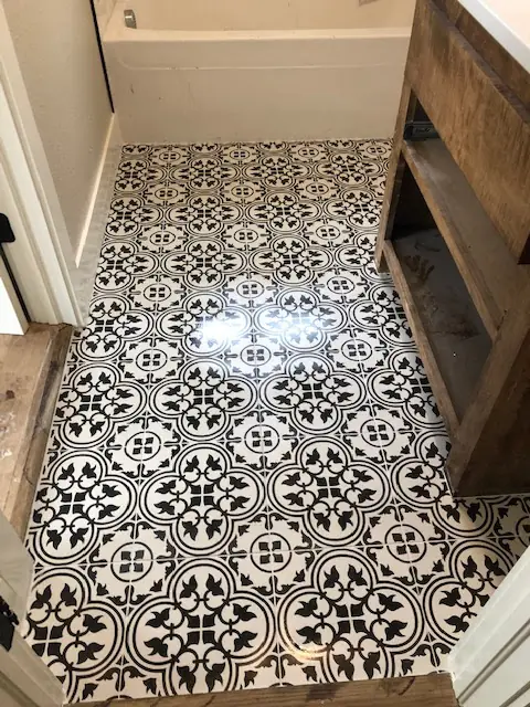 Black-and-white patterned encaustic-look tile floor installed beside rustic wood shelving