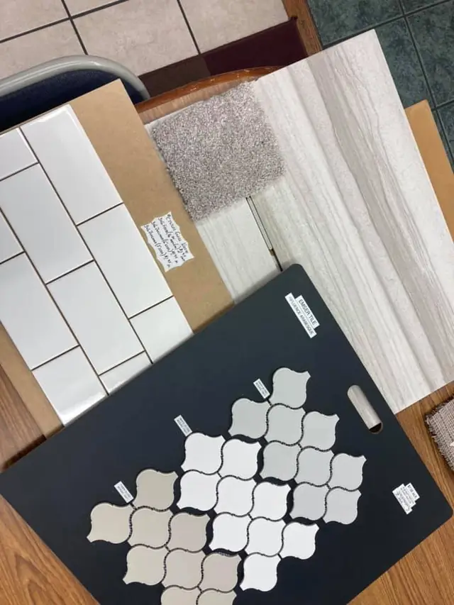 Selection table with an arabesque mosaic board, subway tile, a carpet swatch and metal trim samples laid out together
